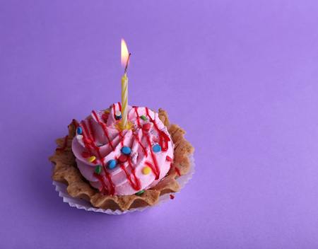 Cake with birthday candle on purple backgroundの写真素材