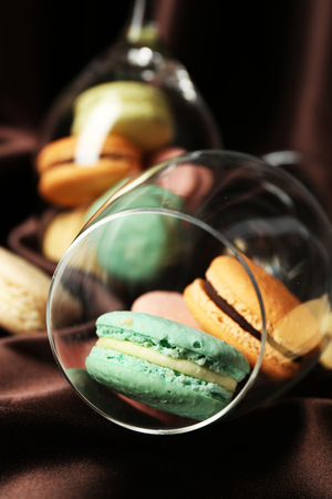 Gentle colorful macaroons in wine glass on color fabric backgroundの写真素材