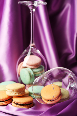 Gentle colorful macaroons in wine glass on color fabric backgroundの写真素材