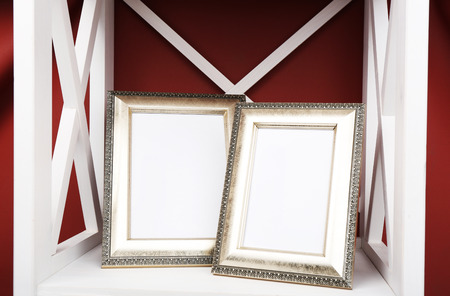 Two photo frames on shelf, on color wall backgroundの写真素材