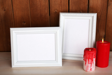 Photo frames with candles and books on wooden surface and wooden wall backgroundの写真素材