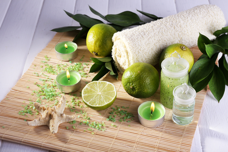 Spa composition with lime, towel and candles on bamboo mat and color wooden backgroundの写真素材