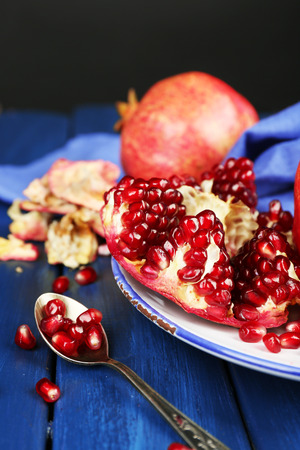 Juicy ripe pomegranates on wooden table, on dark backgroundの写真素材