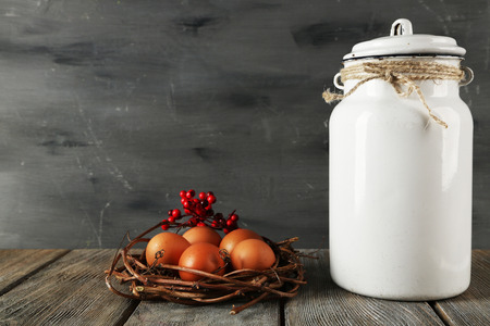 Milk can with eggs on wooden table and dark backgroundの写真素材