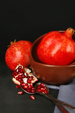Juicy ripe pomegranates on wooden table, on dark backgroundの写真素材
