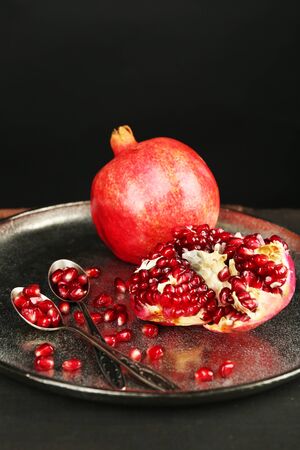 Juicy ripe pomegranates on metal plate, on dark backgroundの写真素材