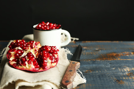 Juicy ripe pomegranate on wooden table, on dark backgroundの写真素材