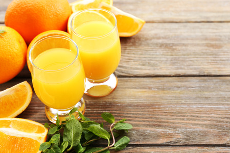 Glass of orange juice and slices on wooden table backgroundの写真素材