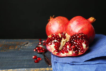 Juicy ripe pomegranates on wooden table, on dark backgroundの写真素材