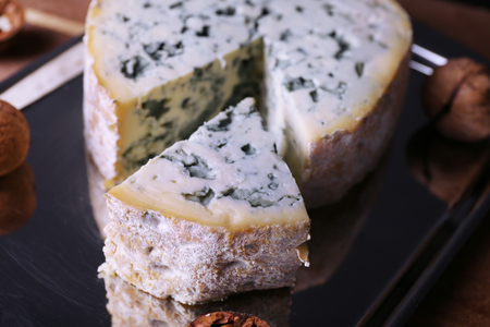 Blue cheese with nuts on metal tray and wooden table backgroundの写真素材