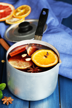 Old metal pan of tasty mulled wine on wooden tableの写真素材