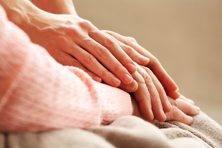 Old and young holding hands on light background