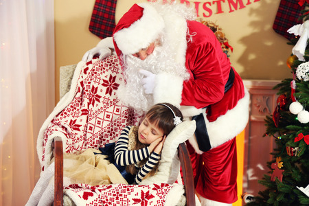Santa Claus giving  present to sleeping little cute girl Christmas tree at homeの写真素材