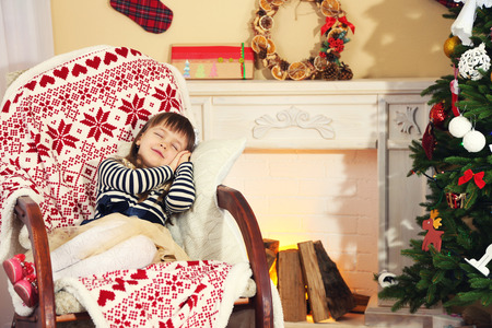 Little girl sitting in rocking chair near fireplace の写真素材