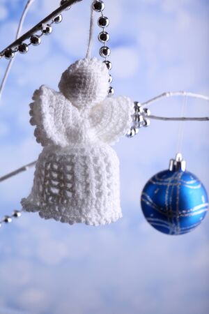 Knitted Christmas angel hanging on bud on light background の写真素材