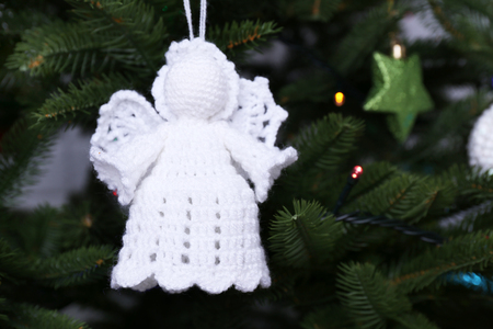 Knitted Christmas angels and other decorations on Christmas tree background, close-up の写真素材