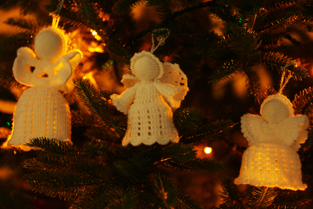 Knitted Christmas angels on Christmas lights backgroundの写真素材