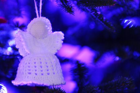 Knitted Christmas angel on Christmas lights backgroundの写真素材