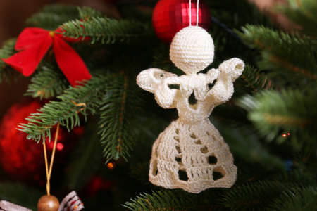 Knitted Christmas angels and other decorations on Christmas tree background, close-up の写真素材
