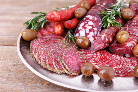 Sliced smoked sausages on metal tray on wooden table backgroundの写真素材