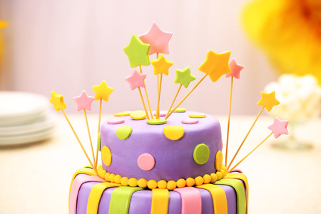 Delicious birthday cake on table on bright background