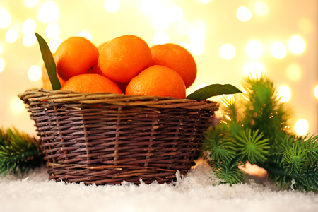 Fresh ripe mandarins in wicker basket, on snow, on lights backgroundの写真素材
