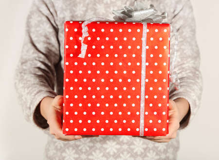 Female hands holding present box with ribbon on light background