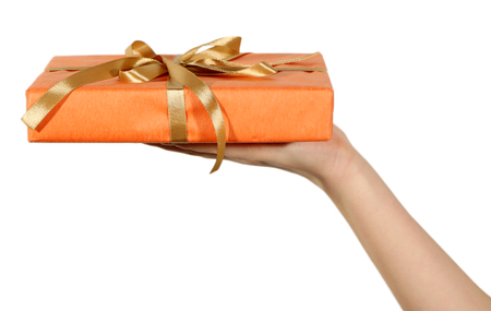 Female hand holding present box with ribbon on light backgroundの写真素材