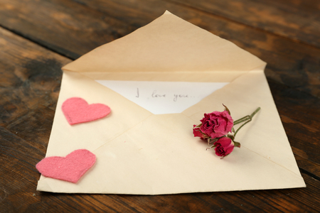 Envelope with love letter and dried rose on rustic wooden table backgroundの写真素材