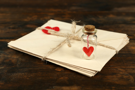 Stack of love letters with little bottle on rustic wooden table background