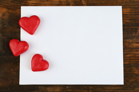 Blank sheet of paper with hearts on rustic wooden table backgroundの写真素材