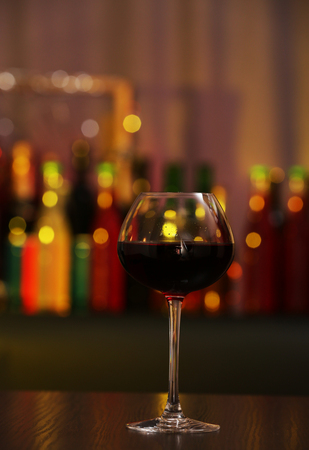 Glass of red wine in bar on blurred backgroundの写真素材