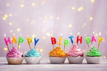 Delicious birthday cupcakes on table on light backgroundの写真素材