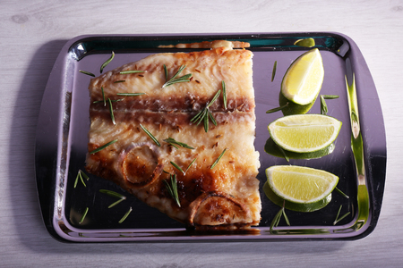 Dish of Pangasius fillet with rosemary and lime on metal tray and color wooden table backgroundの写真素材