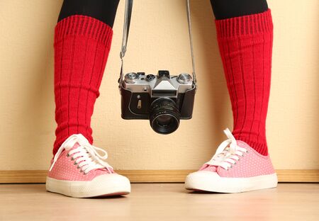 Girl in sneakers with retro photo camera in roomの写真素材