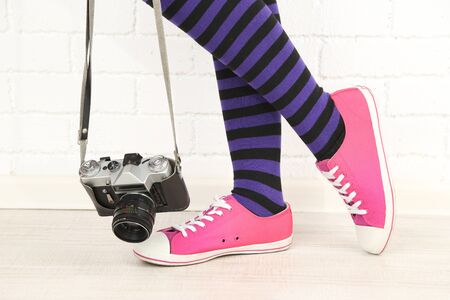 Girl in sneakers with retro photo camera in roomの写真素材