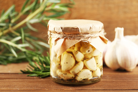 Canned garlic in glass jar on wooden backgroundの写真素材