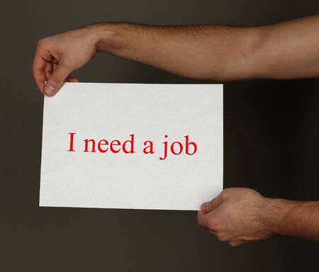 Sheet of paper with inscription I need a job in male hands on dark backgroundの写真素材