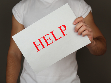 Sheet of paper with Help sign in male hand on dark backgroundの写真素材