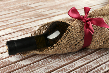 Wine bottle wrapped in burlap cloth on wooden planks backgroundの写真素材