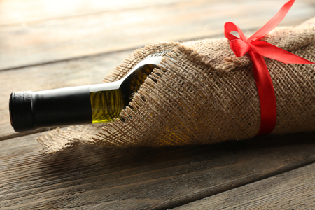 Wine bottle wrapped in burlap cloth on wooden planks backgroundの写真素材