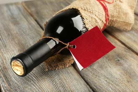 Wine bottle wrapped in burlap cloth on wooden planks backgroundの写真素材
