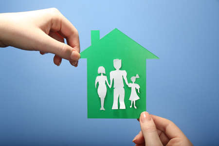 Cutout house with paper family in female hands on colorful backgroundの写真素材