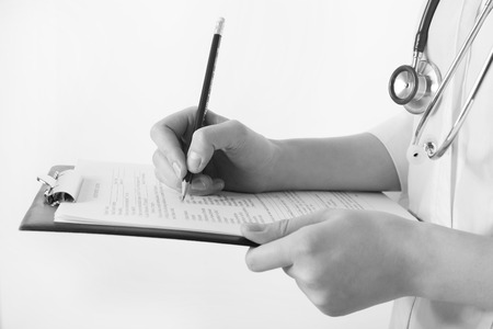 Doctor writing on clipboard on light backgroundの写真素材