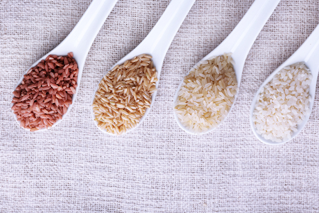 Different types of rice in spoons on fabric backgroundの写真素材
