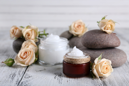 Cosmetic cream with flowers and spa stones on wooden backgroundの写真素材