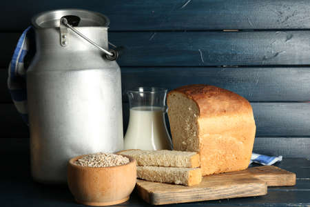 Retro can for milk with fresh bread and glass jug of milk on wooden background. Bio products conceptの写真素材