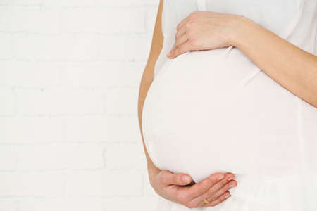 Young pregnant woman on light background