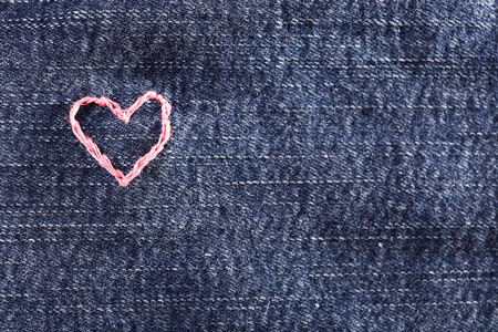 Jeans fabric with pink heart embroidered on it, close-upの写真素材