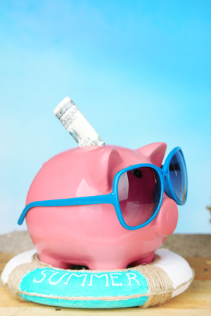 Piggy bank with sunglasses on wooden table, outdoorsの写真素材